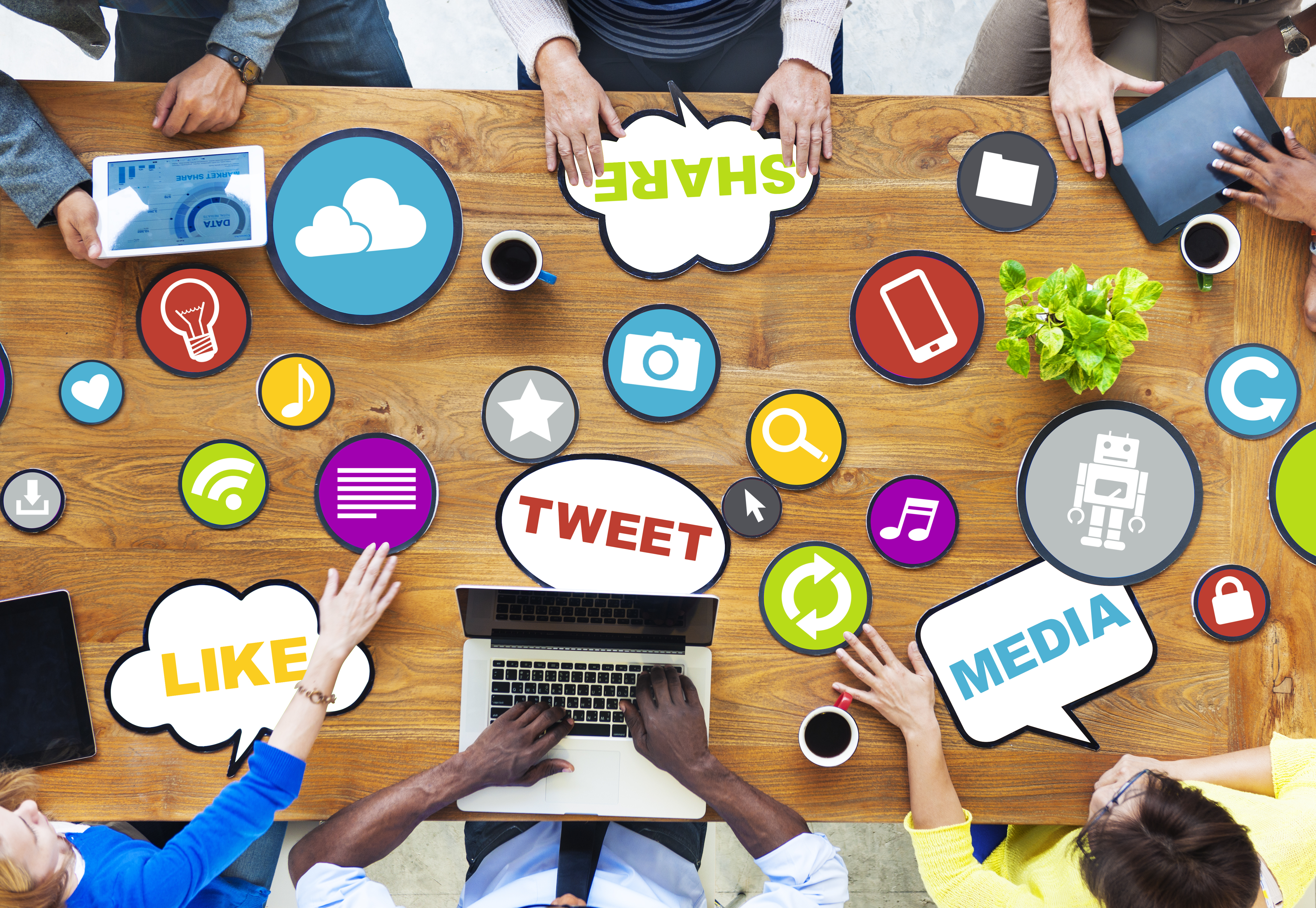 image of a team meeting at a conference table covered in social media symbols to discuss social media marketing